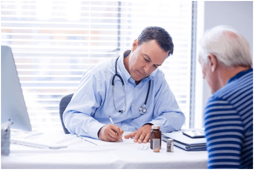 A doctor writing on paper while sitting at a table.