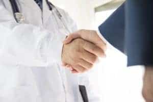 Two doctors shaking hands in a room.