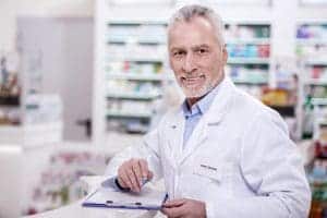 A man in white lab coat holding a clipboard.