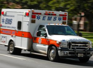 A white and orange ambulance is driving down the street.